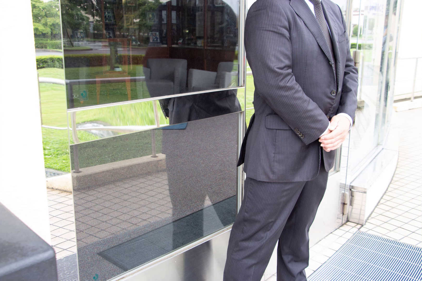 Suited Zone security officer standing at a glass entrance